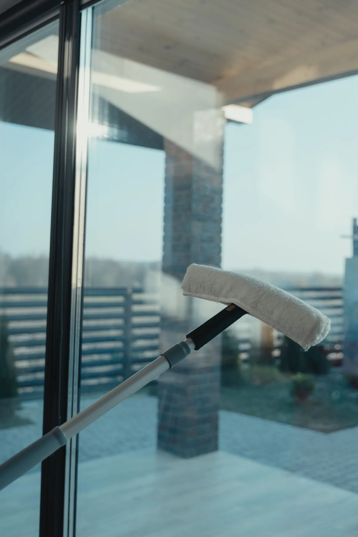 A cleaning pad wetting a tall pane of glass