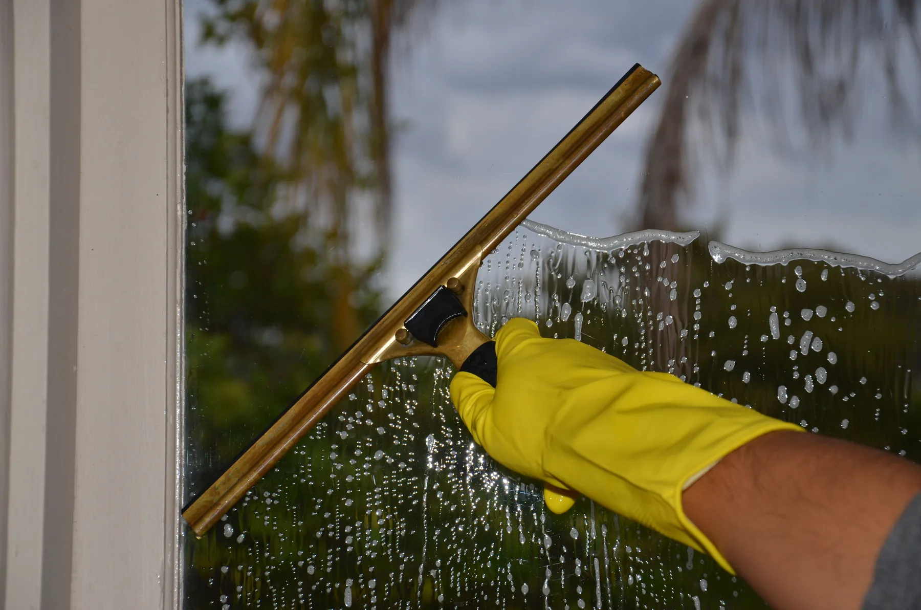 A squeegee pulling water down a clean window